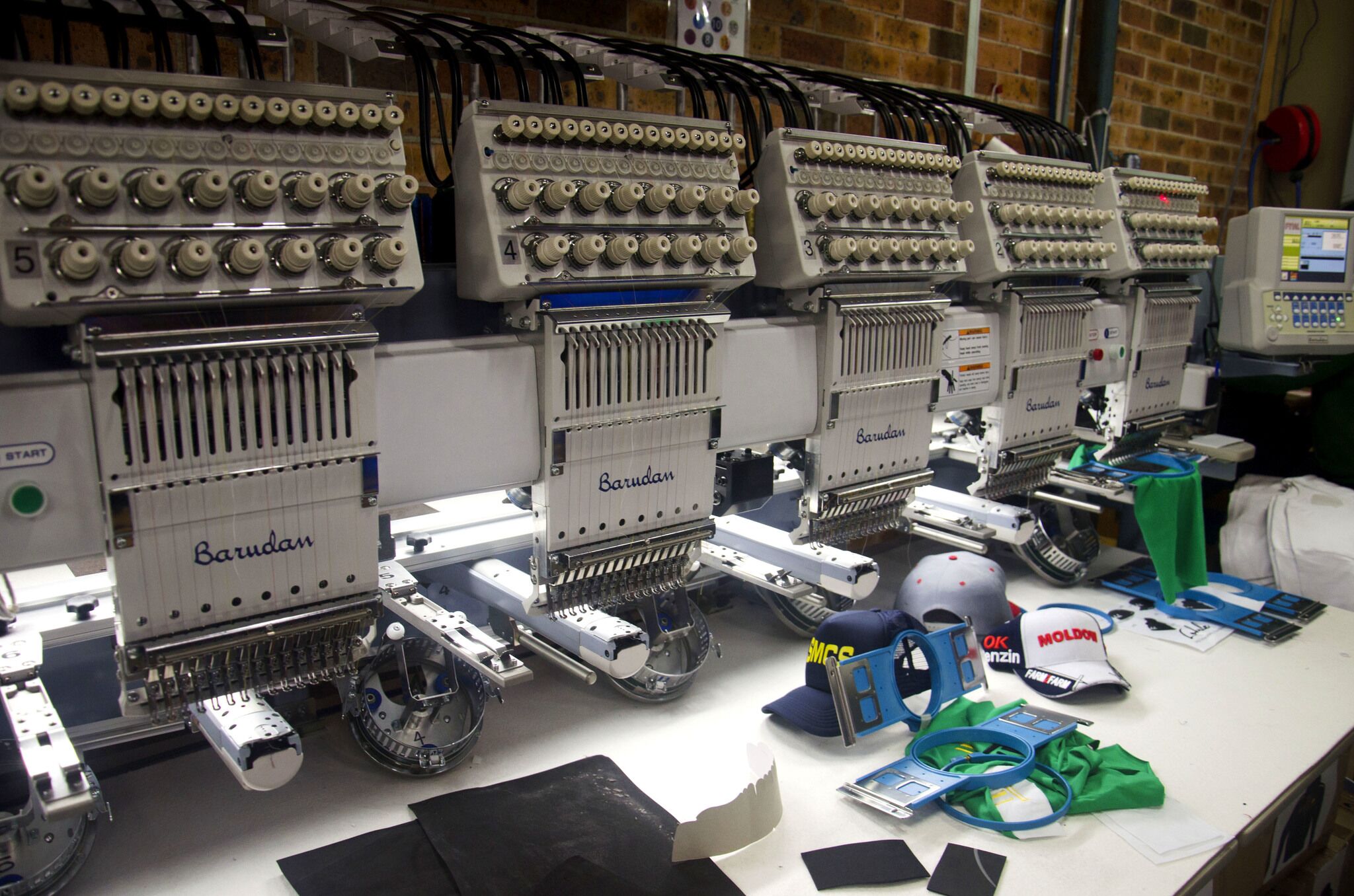 Commercial embroidery machines and cap frames in a production shop.