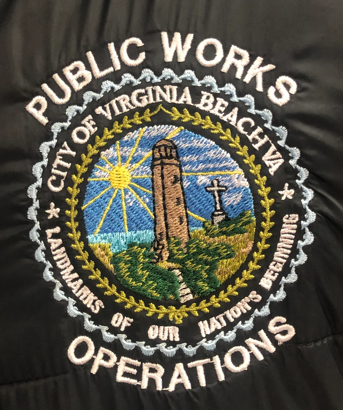 Detailed multicolor Virginia Beach public works emblem embroidered on black quilted outerwear